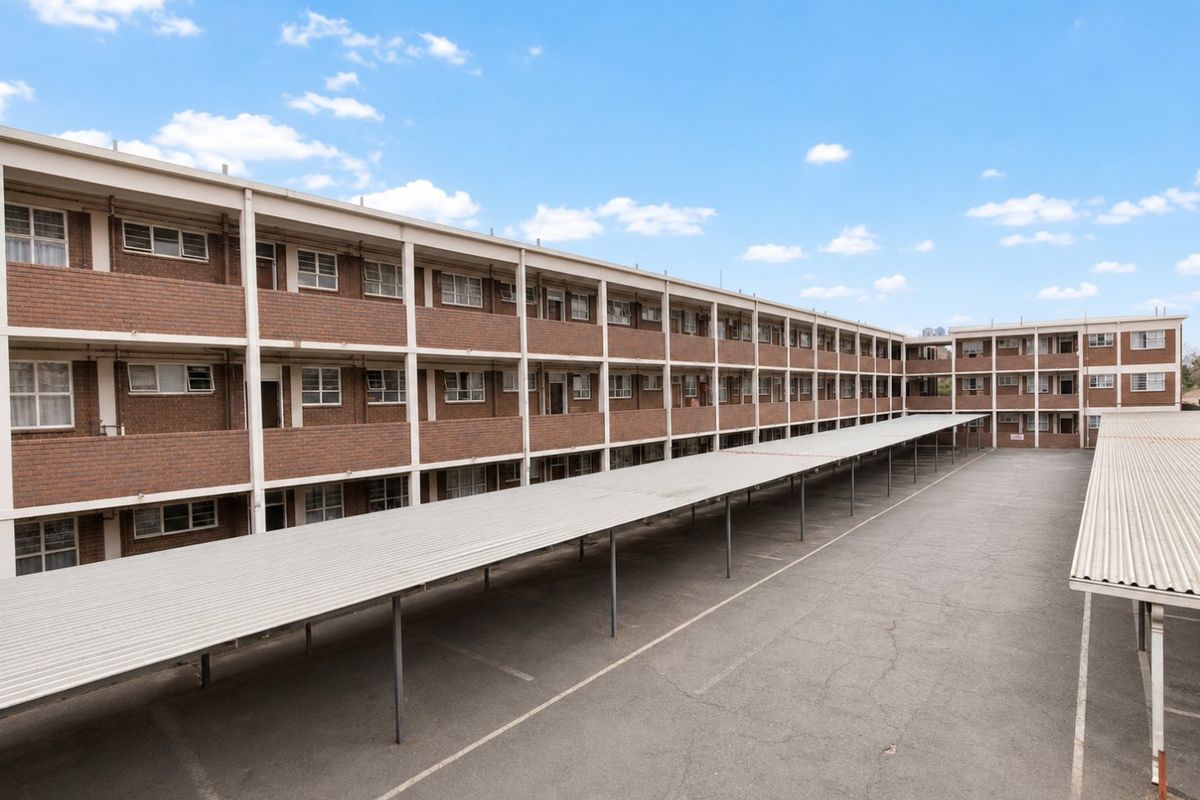 Exterior view of a multi-story apartment complex featuring brick facade construction and extensive covered parking facilities.