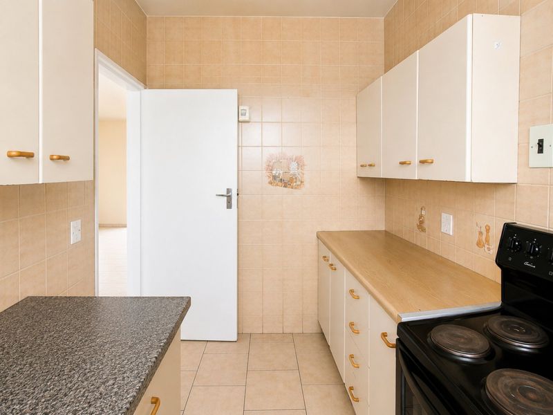 A functional kitchen featuring built-in cabinetry, laminate countertops, tiled splashbacks, and an electric stove, offering a clean and practical layout.