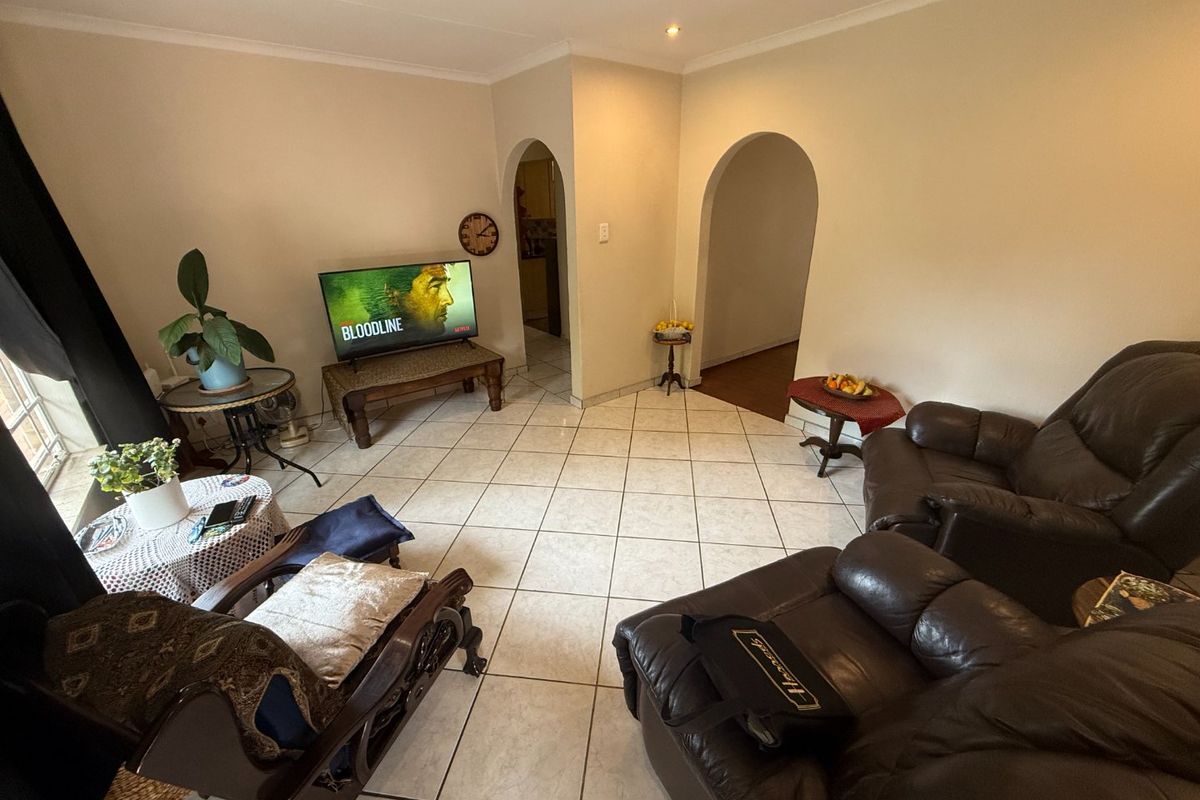 A spacious living room featuring neutral tiled flooring and distinctive arched doorways leading to adjacent areas of the home.