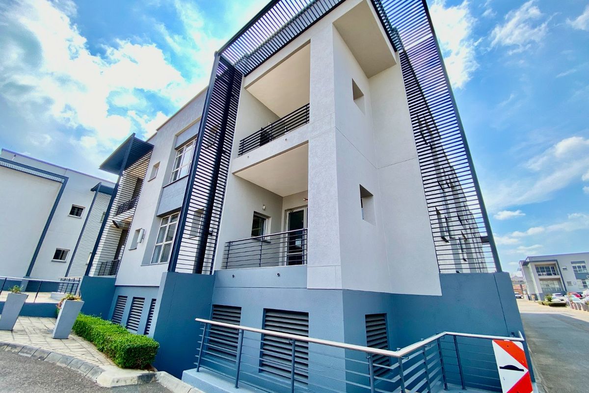 Modern commercial building exterior featuring multi-level balconies, decorative metal louvre screens, and a clean, contemporary facade design.