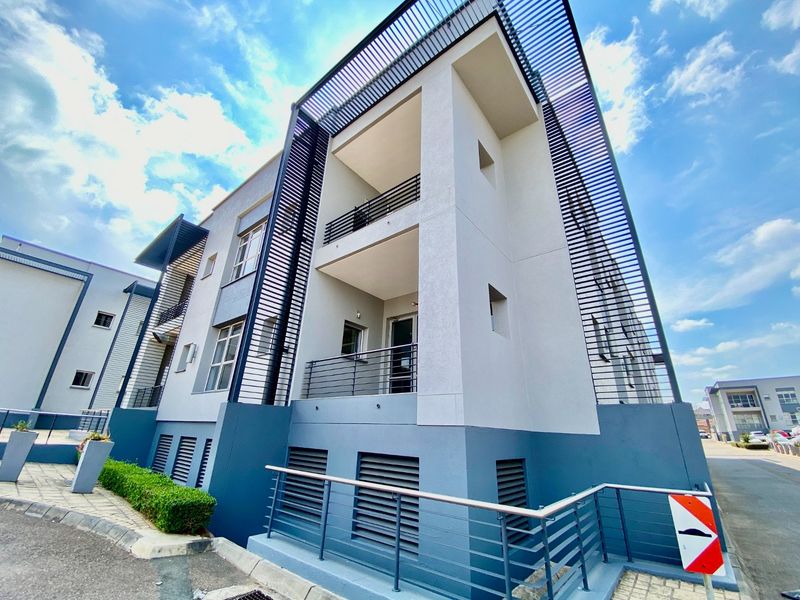 Modern commercial building exterior featuring multi-level balconies, decorative metal louvre screens, and a clean, contemporary facade design.