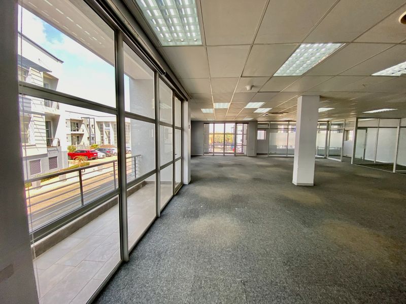 Open plan office space featuring large glass windows, suspended ceilings with recessed lighting, and carpeted flooring, offering a bright and versatile commercial workspace.