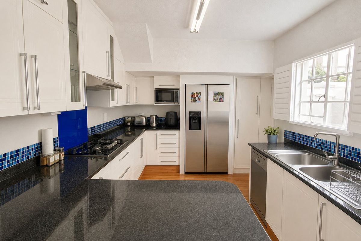 Modern kitchen featuring white shaker cabinetry, dark granite countertops, blue mosaic tile splashback, gas hob, and integrated appliances.