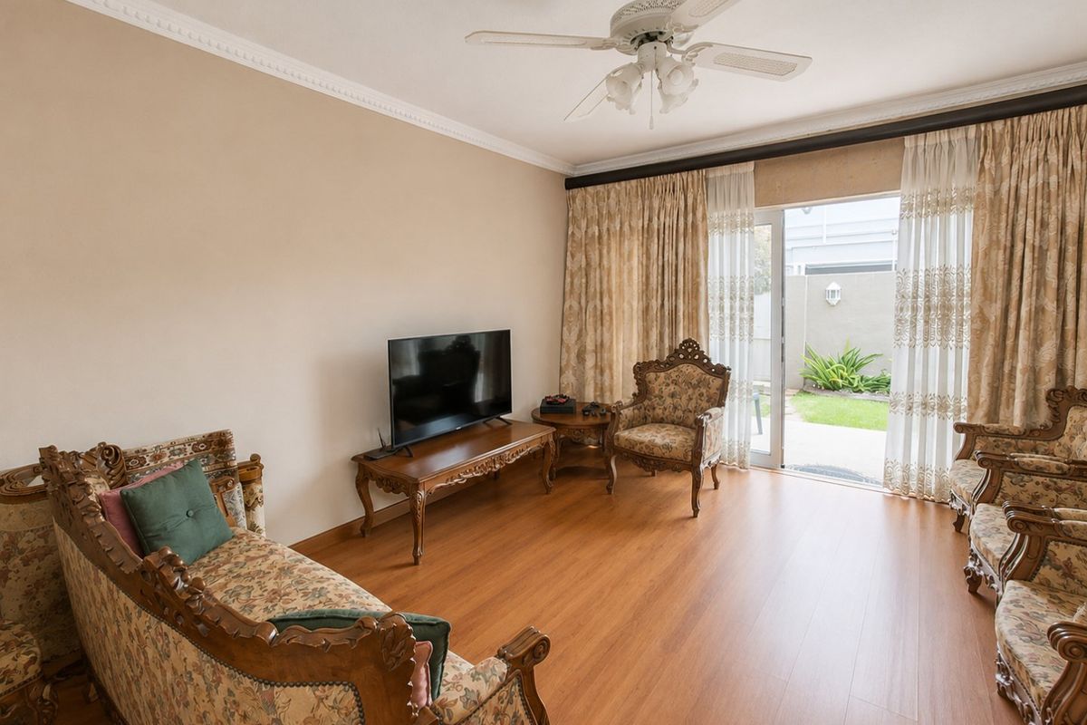 A living room featuring laminate flooring, a ceiling fan, and sliding glass doors providing direct access to the rear garden area.