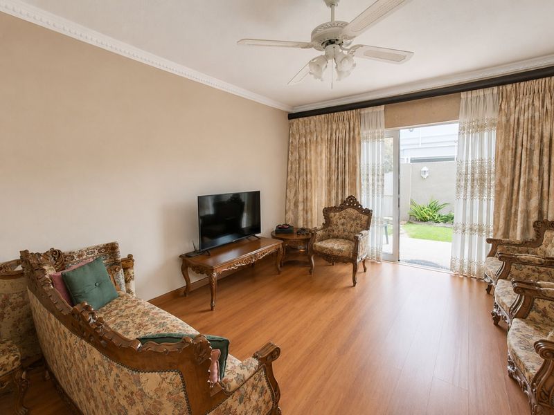 A living room featuring laminate flooring, a ceiling fan, and sliding glass doors providing direct access to the rear garden area.