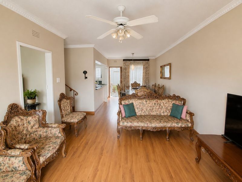 Spacious open-plan living and dining area featuring laminate flooring, crown molding, and a ceiling fan, with a convenient pass-through to the kitchen area.