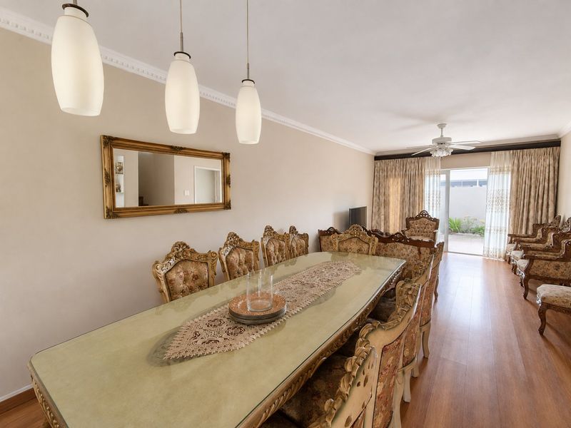Spacious dining area featuring laminate flooring, crown molding, and pendant lighting, with direct access to the outdoor patio through sliding glass doors.