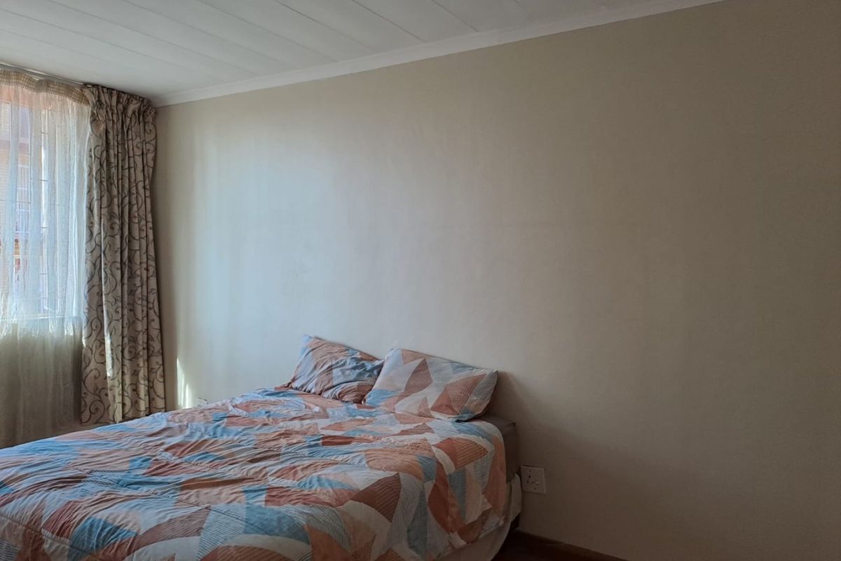 A simple bedroom featuring neutral walls, a tongue and groove ceiling, and standard electrical fixtures.