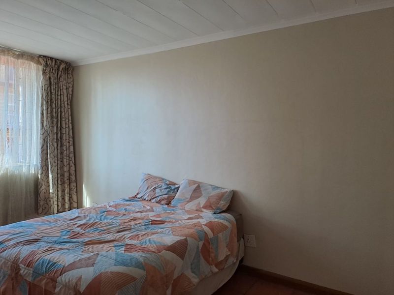 A simple bedroom featuring neutral walls, a tongue and groove ceiling, and standard electrical fixtures.