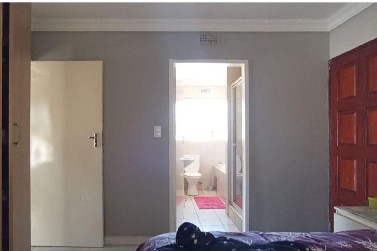 A bedroom featuring a built-in wardrobe and direct access to an en-suite bathroom with tiled flooring and neutral wall finishes.