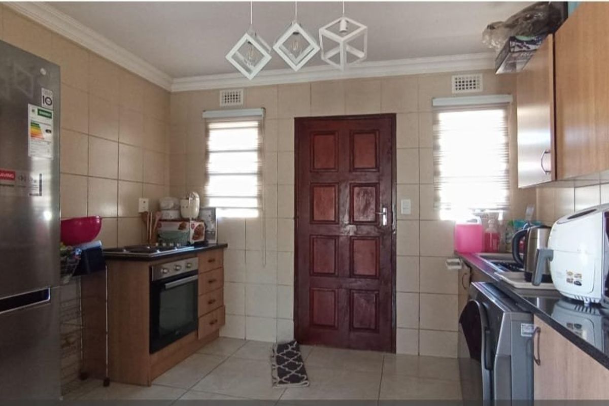 Functional kitchen featuring built-in cabinetry, granite countertops, integrated oven and hob, tiled splashbacks, and tiled flooring with direct access to an exterior door.