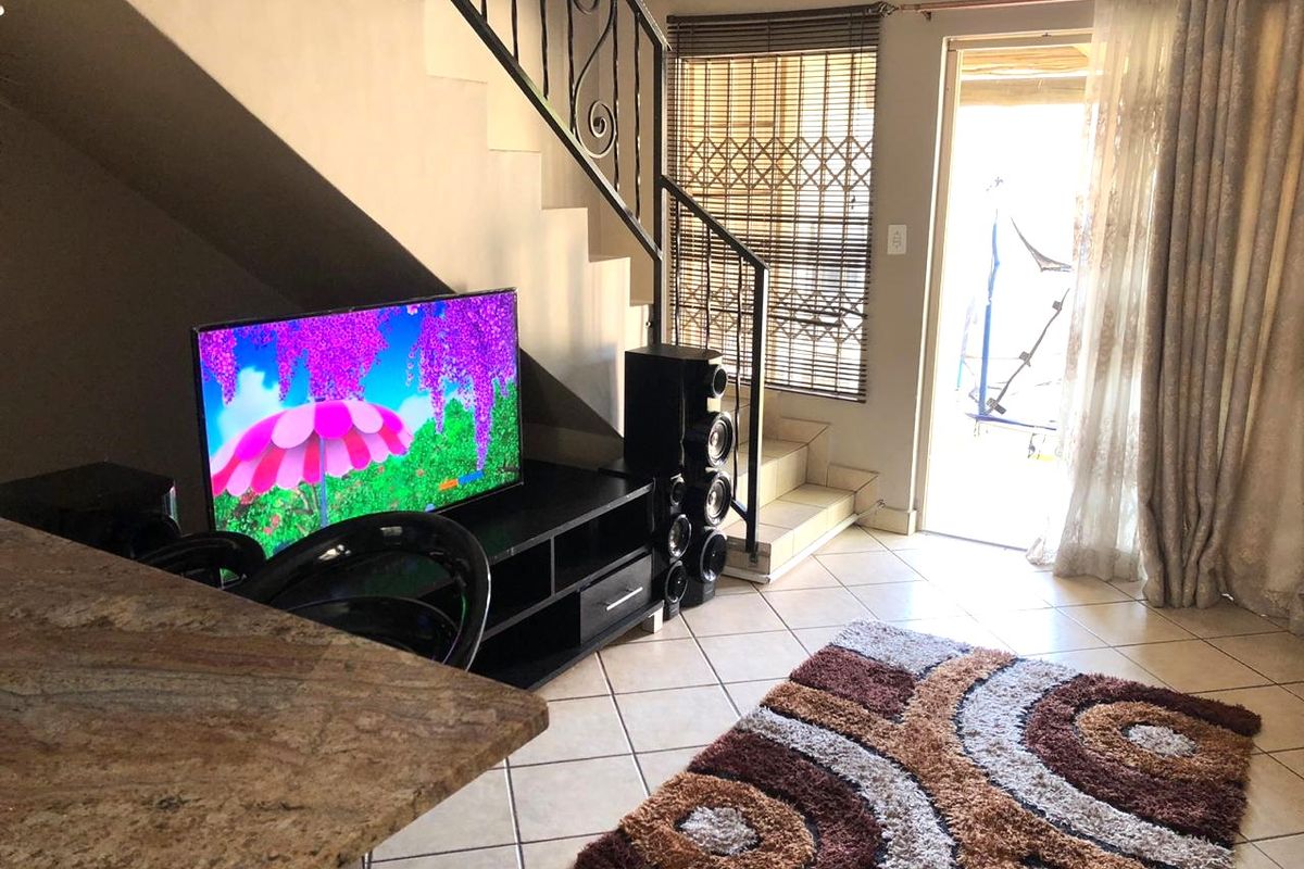 Living area featuring tiled flooring, a staircase with a wrought iron balustrade, and direct access to an outdoor patio area.
