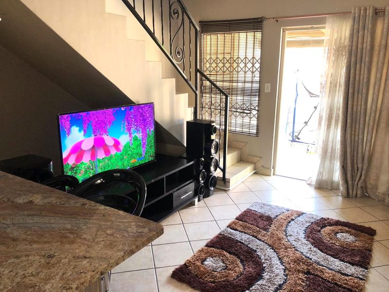 Living area featuring tiled flooring, a staircase with a wrought iron balustrade, and direct access to an outdoor patio area.