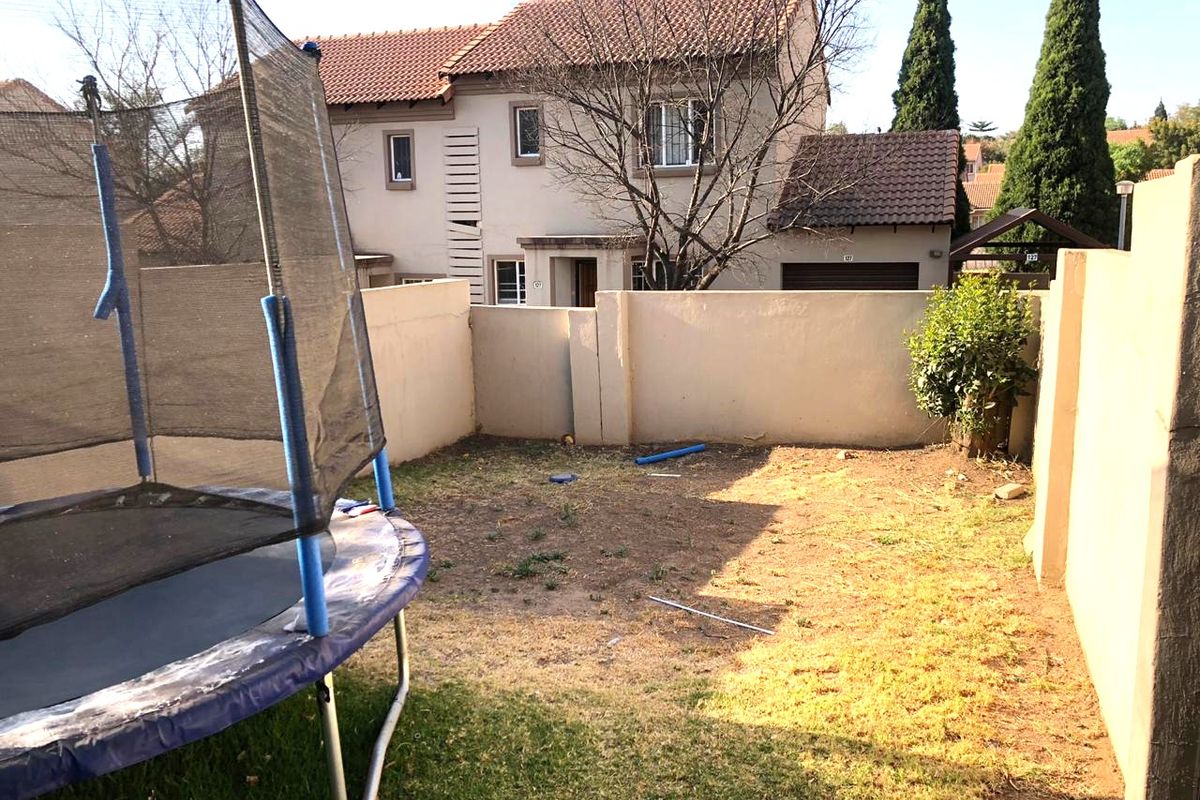 A rear garden area featuring a boundary wall and views of the townhouse facade with a tiled roof.