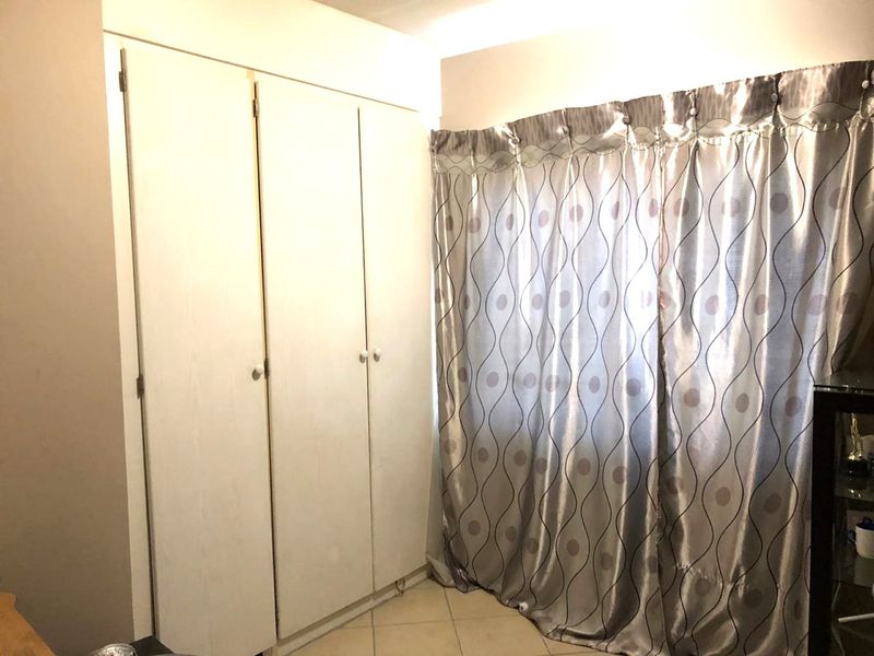 A bedroom featuring built-in wardrobes and tiled flooring, providing functional storage space.