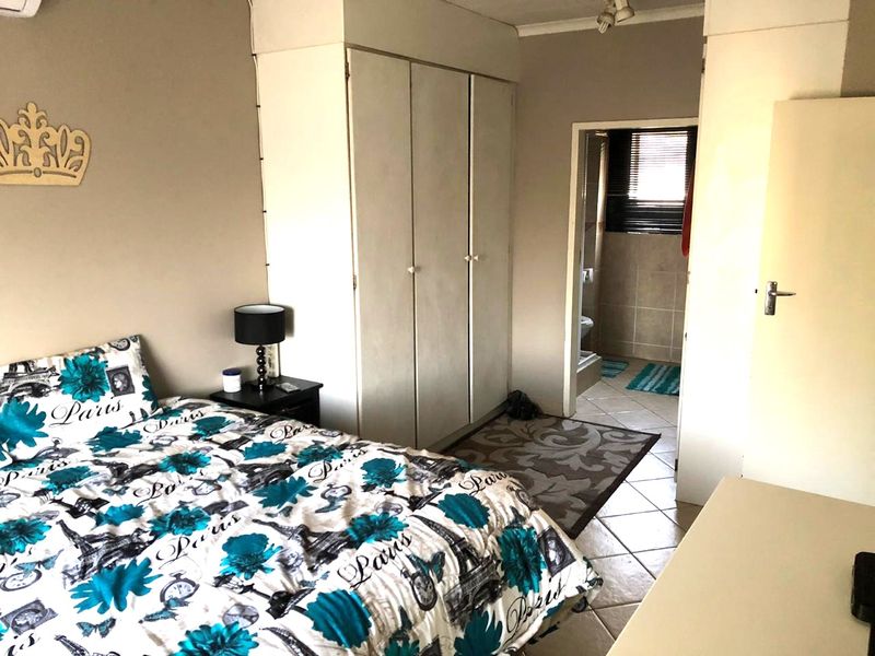 Bedroom featuring built-in wardrobes, tiled flooring, and direct access to an en-suite bathroom.