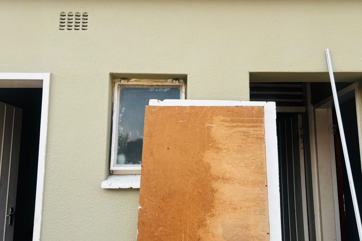 Exterior view of a building facade showing window and door frames with visible signs of weathering and maintenance requirements.