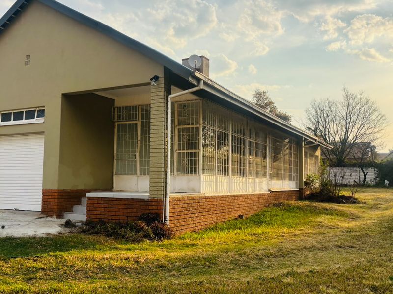 Rear view of the house featuring a brick base, enclosed patio with security bars, and a single roller garage door with a concrete driveway.
