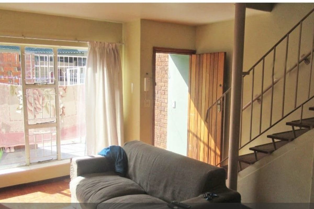 Living room area featuring a staircase with metal handrail, sliding glass door access to the exterior, and a wooden entrance door.