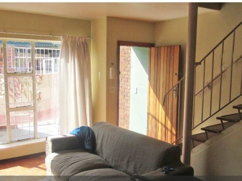 Living room area featuring a staircase with metal handrail, sliding glass door access to the exterior, and a wooden entrance door.