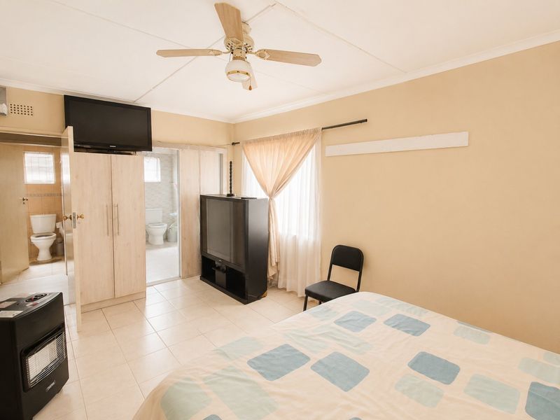 Bedroom featuring tiled flooring, a ceiling fan, and an en-suite bathroom with a toilet.