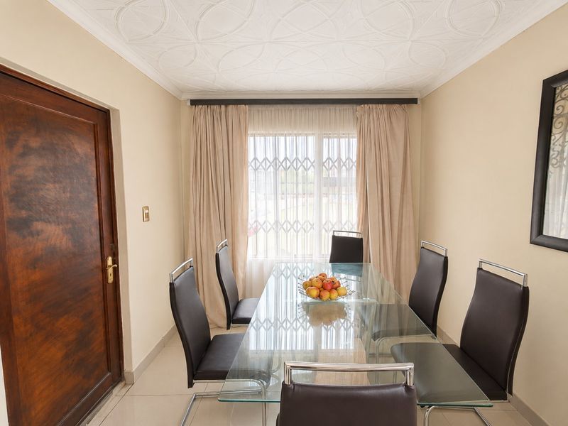 A dining room featuring tiled flooring, a decorative patterned ceiling, and a window fitted with a security gate.