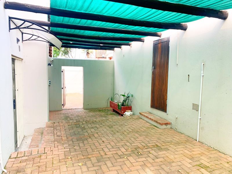 A paved outdoor patio area featuring a timber pergola with shade cloth, providing a functional and private space for outdoor living.