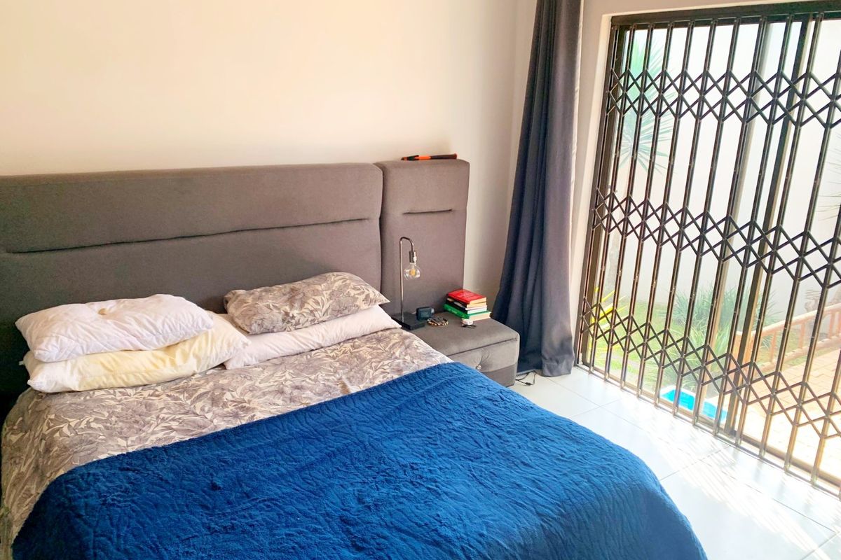 A bedroom featuring tiled flooring and a sliding door with a security gate providing access to the exterior.
