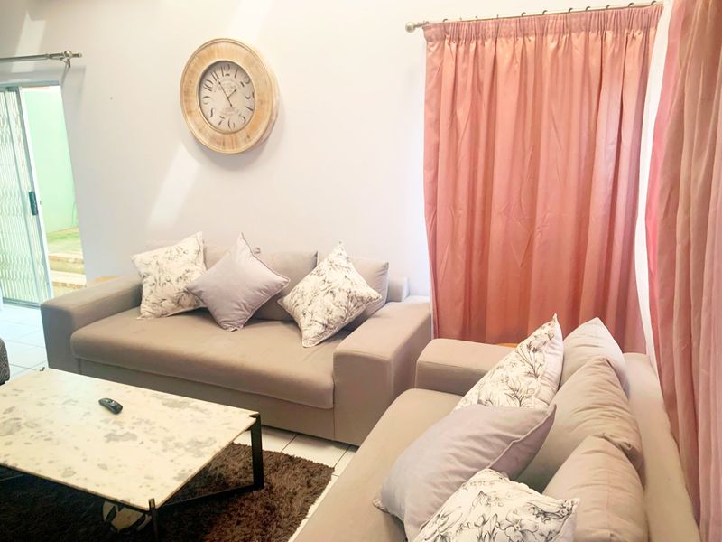 A bright living room featuring tiled flooring and a sliding glass door leading to an outdoor area.