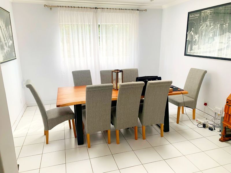 A bright dining room featuring neutral ceramic tile flooring and clean white walls, providing a functional space for family meals.
