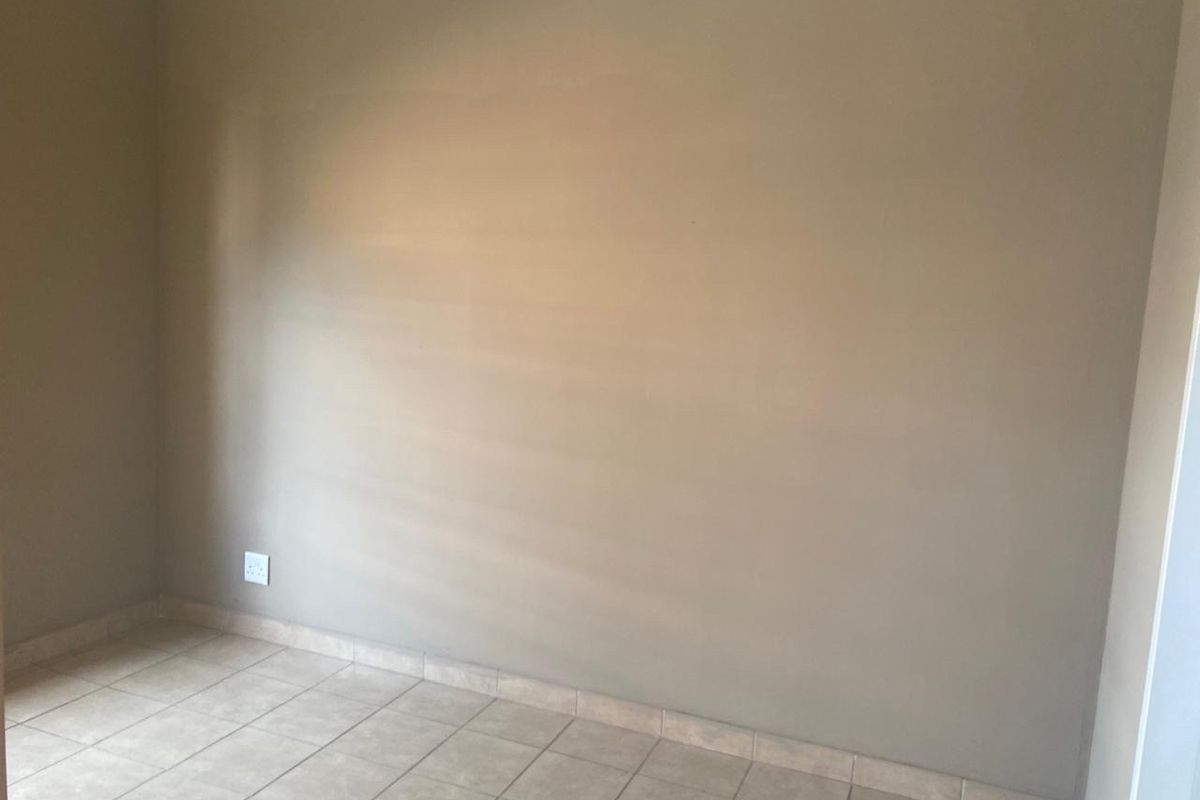 An empty bedroom featuring neutral-toned walls and tiled flooring, providing a blank canvas for personalization.