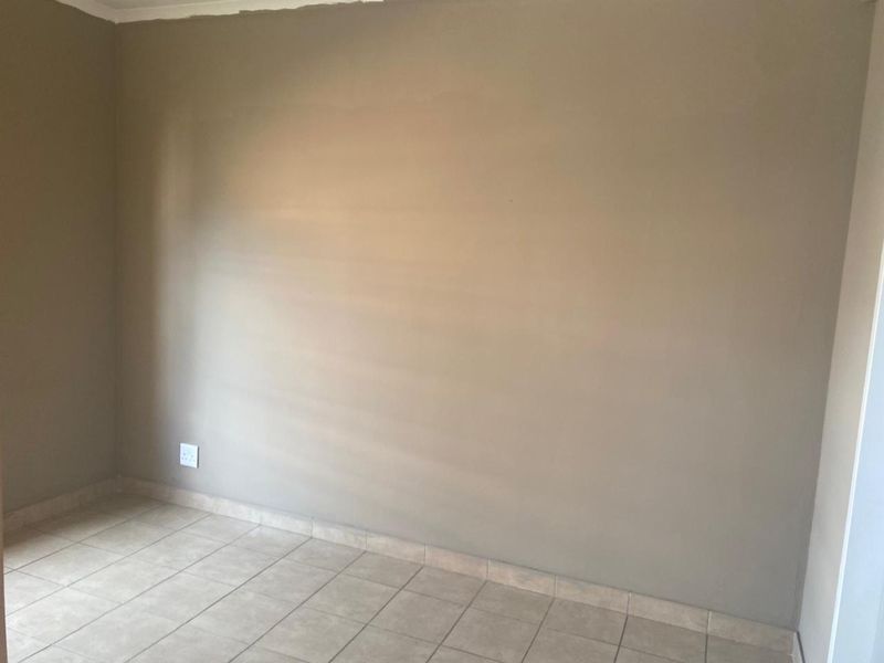 An empty bedroom featuring neutral-toned walls and tiled flooring, providing a blank canvas for personalization.