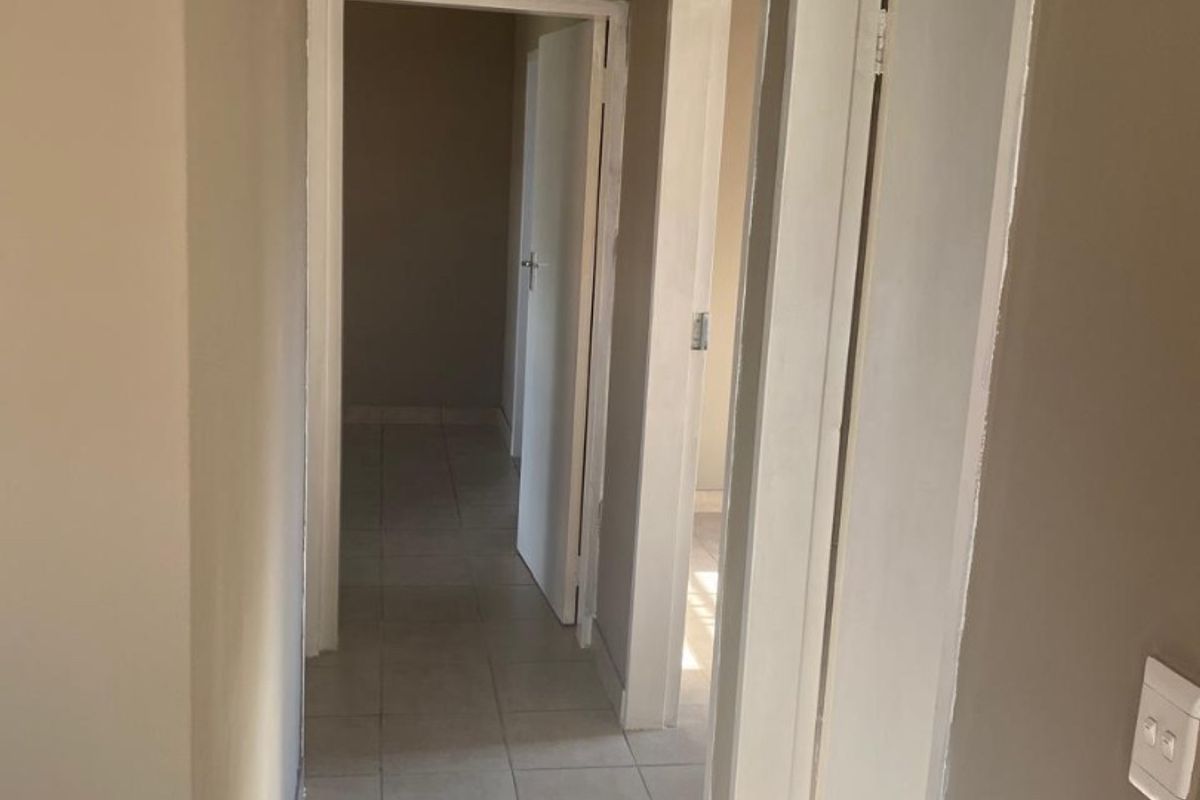 A neutral-toned hallway featuring tiled flooring and multiple internal doorways providing access to adjacent rooms.