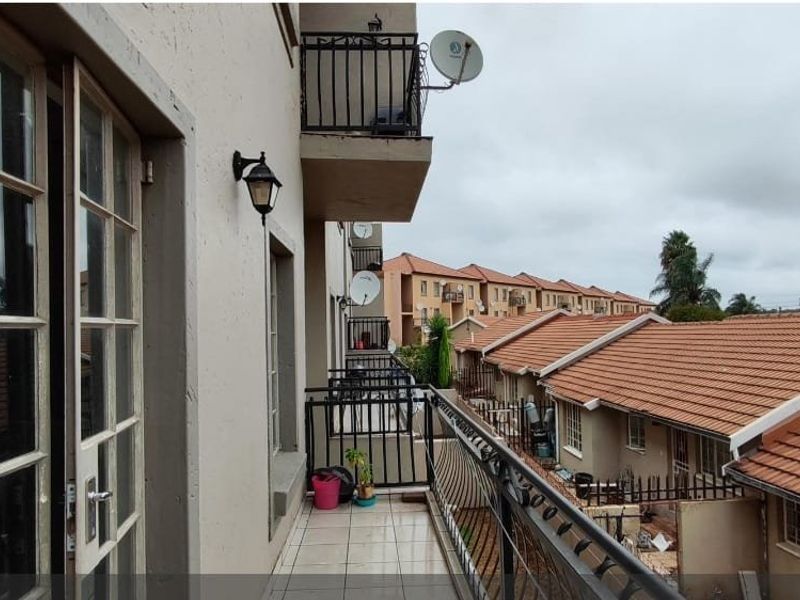 A tiled balcony with a wrought iron balustrade, offering an elevated view of the townhouse complex and surrounding neighborhood.