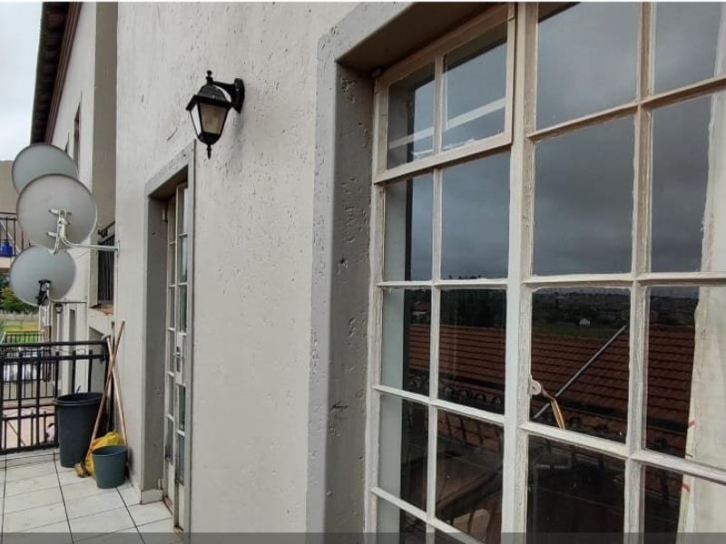 A balcony area featuring tiled flooring, metal balustrades, and multi-pane glass doors, offering an outdoor space with potential for enhancement.