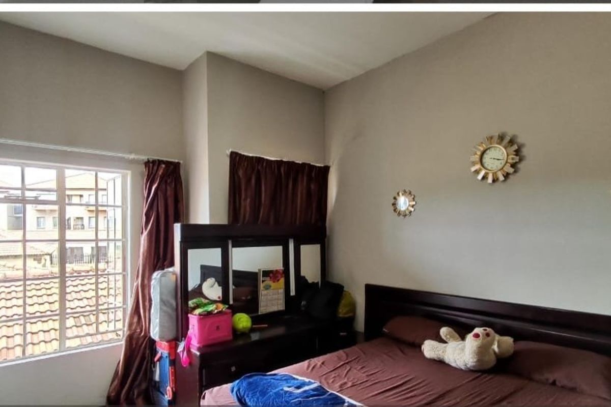 A bedroom featuring a built-in wardrobe and a casement window, providing natural light and views of the surrounding townhouse complex.