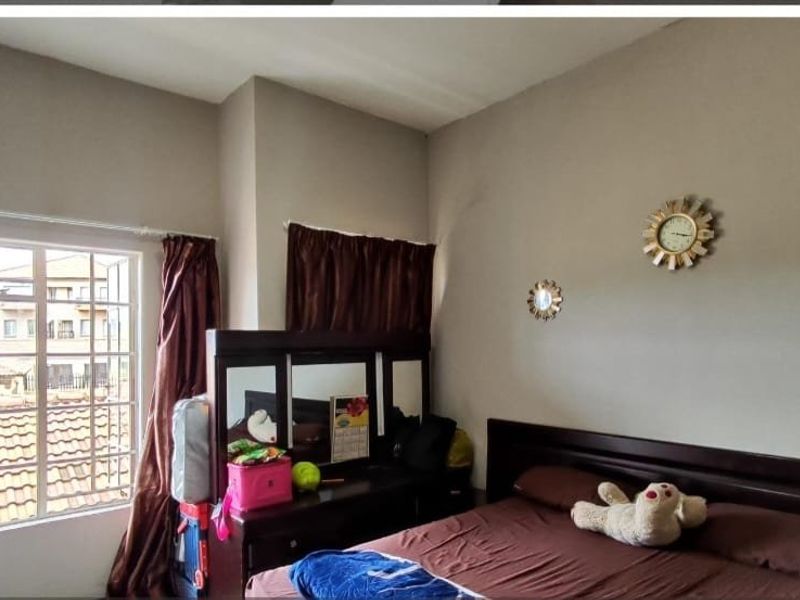 A bedroom featuring a built-in wardrobe and a casement window, providing natural light and views of the surrounding townhouse complex.