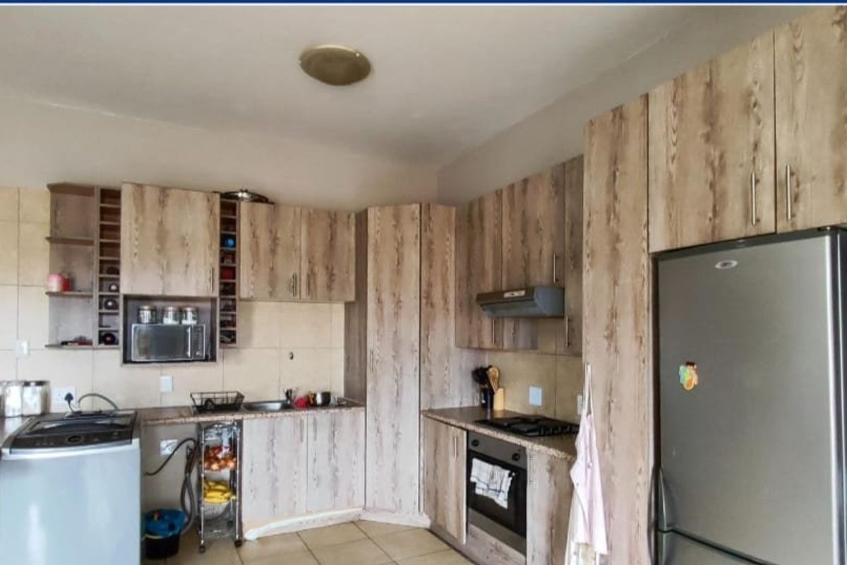 Functional kitchen featuring wood-look cabinetry, built-in oven, hob, extractor fan, and a breakfast bar, providing a practical layout for daily cooking and dining.