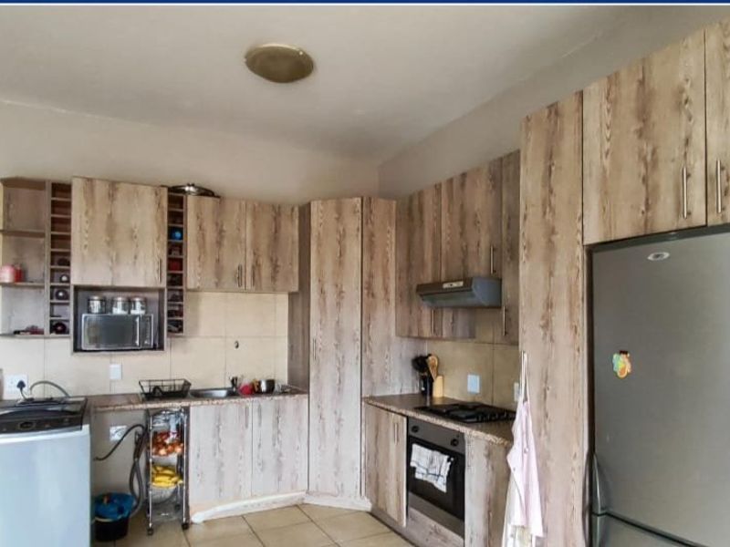 Functional kitchen featuring wood-look cabinetry, built-in oven, hob, extractor fan, and a breakfast bar, providing a practical layout for daily cooking and dining.