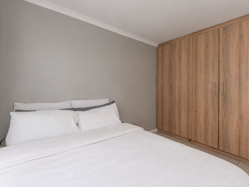 A well-maintained bedroom featuring neutral wall tones and extensive built-in wooden cabinetry for storage.