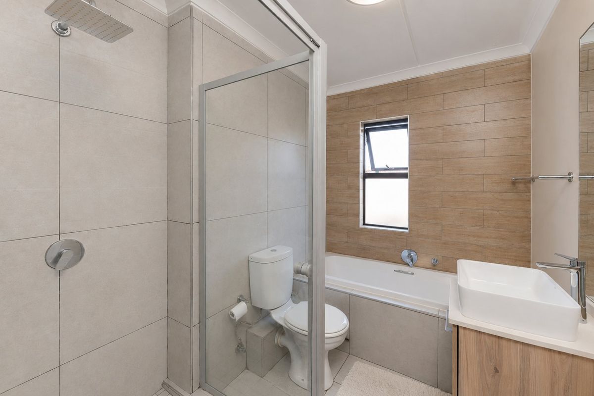 Modern bathroom featuring a walk-in shower with rain head, a separate bathtub, and a contemporary vanity basin with storage cabinet.