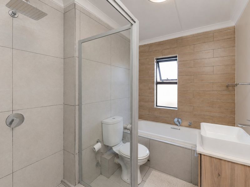 Modern bathroom featuring a walk-in shower with rain head, a separate bathtub, and a contemporary vanity basin with storage cabinet.