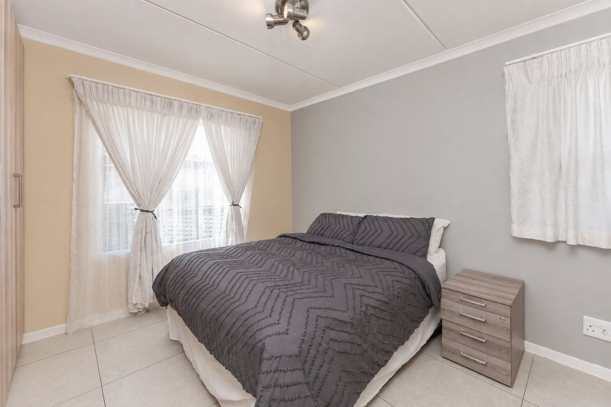 A well-maintained bedroom featuring neutral wall tones, tiled flooring, and a built-in wardrobe, providing a clean and functional living space.