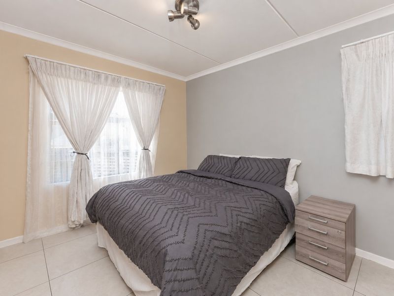 A well-maintained bedroom featuring neutral wall tones, tiled flooring, and a built-in wardrobe, providing a clean and functional living space.