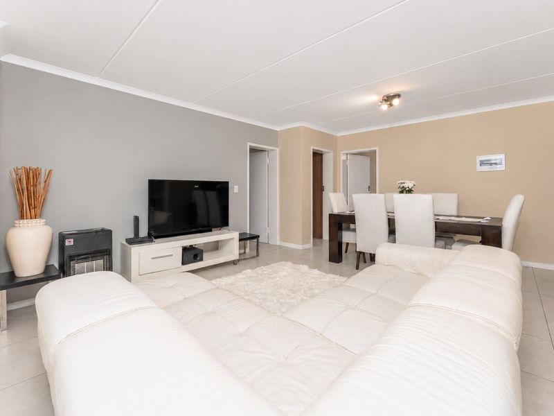 Spacious open-plan living and dining area featuring neutral wall tones, tiled flooring, and clean architectural lines.