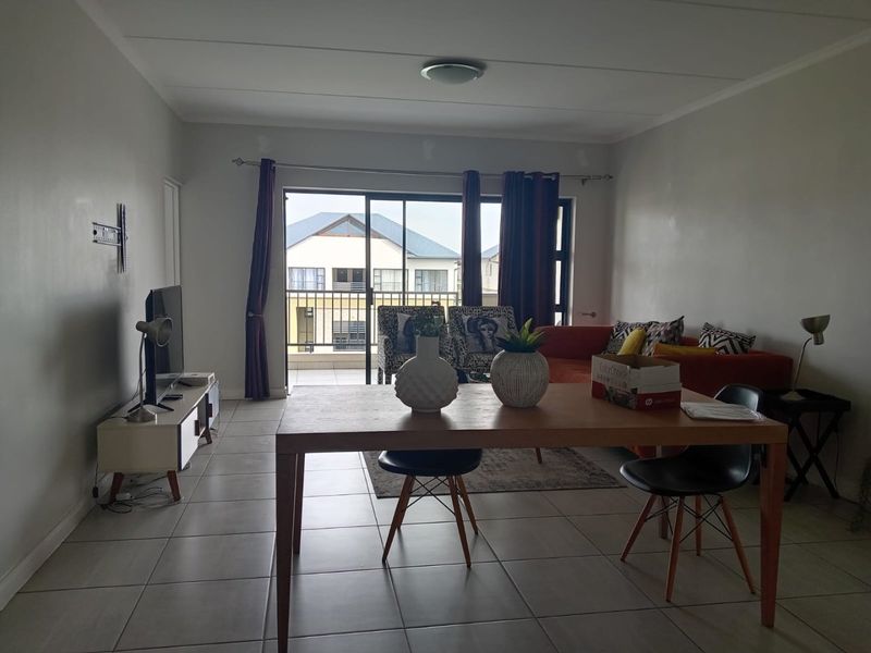 Open plan living and dining area featuring neutral tiled flooring and a large sliding glass door providing access to the balcony.