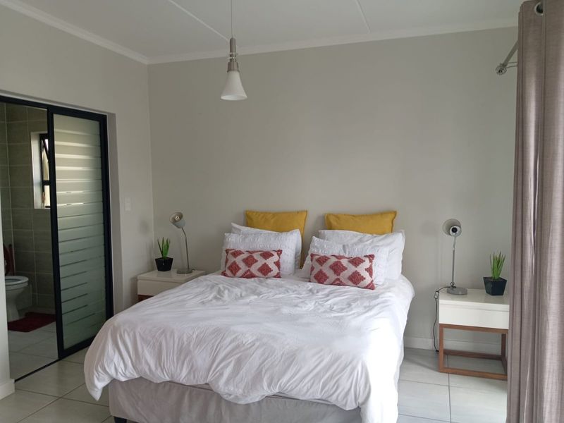 A well-maintained bedroom featuring neutral wall tones, tiled flooring, and direct access to an en-suite bathroom through a modern sliding door.
