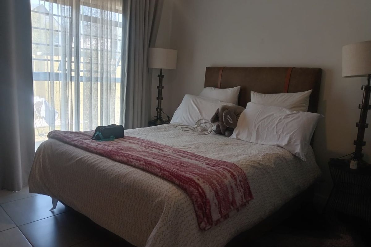 A well-lit bedroom featuring tiled flooring and a large sliding glass door providing access to the exterior.