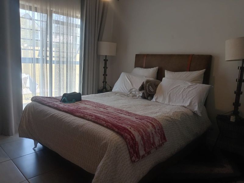 A well-lit bedroom featuring tiled flooring and a large sliding glass door providing access to the exterior.