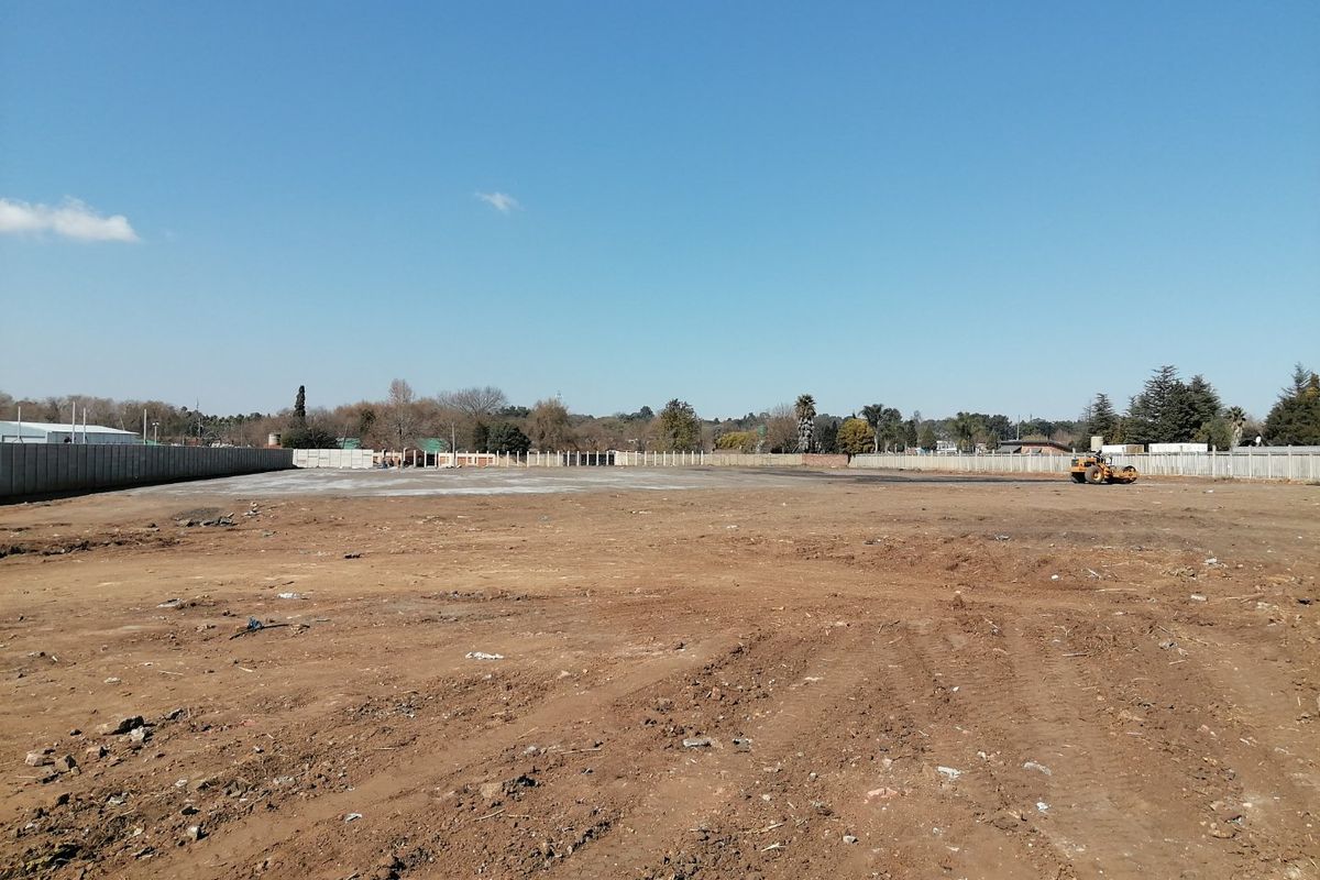 A large, cleared residential vacant land plot enclosed by perimeter concrete walls, ready for development.